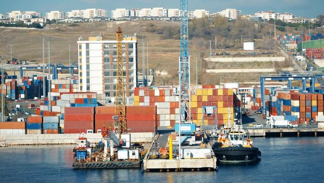4K scene from commercial port in daylight. Calm sea, docked boat, colorful containers and urban landscape stock video.