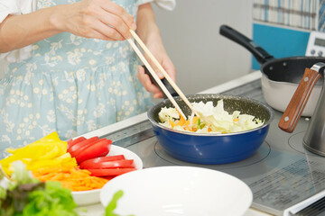 自宅で野菜炒めをする女性　顔無し