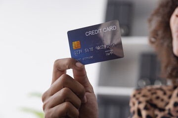 Young African American businesswoman holding credit cards with smartphone sitting at a desk in office. shopping online,