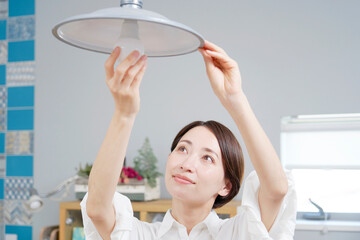 自宅の電球を交換する女性