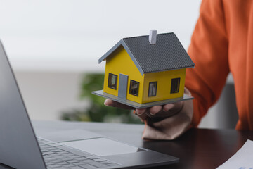 African American businesswoman with house model, Real estate agent and customer discussing for contract to buy house.