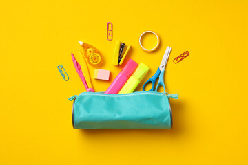 Pencil case with school supplies on yellow background. Back to school concept. Flat lay, top view, overhead.