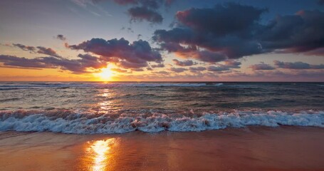Colorful ocean beach sunrise with color sky and sunrays and rolling waves on the sea shore 4K video