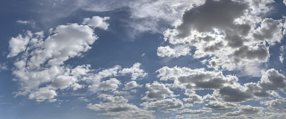 panoramic view of bright blue sky with fluffy clouds in sunny summer day.