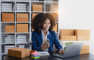 Happy African American businesswoman owner with a parcel box and checking orders from customers, online delivery service warehouse, sell products online concept.