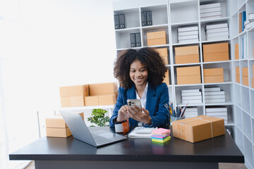 Happy African American businesswoman owner with a parcel box and checking orders from customers, online delivery service warehouse, sell products online concept.