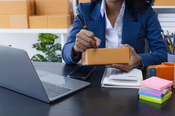 Happy African American businesswoman owner with a parcel box and checking orders from customers, online delivery service warehouse, sell products online concept.
