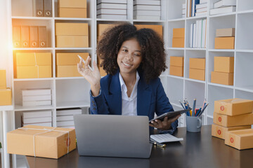 African American owner checking orders from customers sitting at desk in office, sell products online concept.