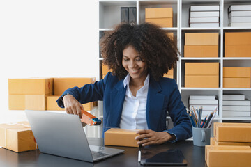 African American owner checking orders from customers sitting at desk in office, sell products online concept.