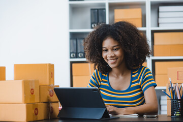 African American owner checking orders from customers sitting at desk in office, sell products online concept.