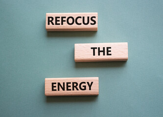 Refocus the Energy symbol. Concept word Refocus the Energy on wooden blocks. Beautiful grey green background. Business and Refocus the Energy concept. Copy space
