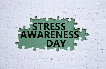 Stress Awareness Day symbol. White puzzle with words Stress Awareness Day. Beautiful grey green background. Business and Stress Awareness Day concept. Copy space.