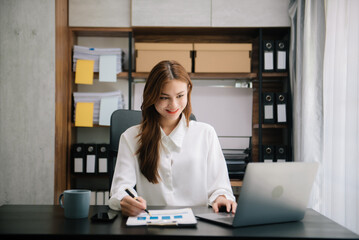 Young beautiful woman typing on tablet and laptop while sitting at the working wooden table office.