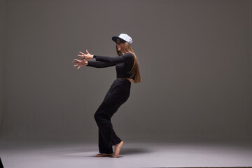 a girl in dark clothes dances and jumps on a dark background background modern dance