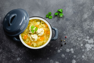 Healthy vegetable noodle meatball soup in pot on dark background. Top view, copy space, flat lay.