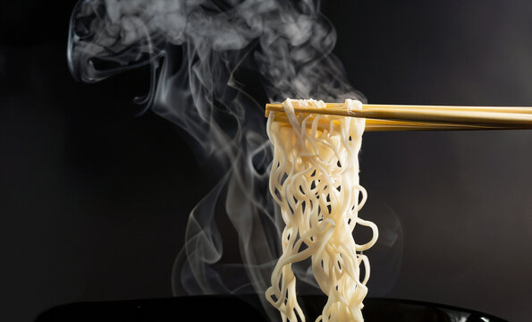 Chopsticks noodles with steam and smoke on black background. selective focus., korea, japan, china, Vietnam and Asian noodle junk food concept