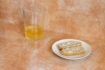 A small plate with two whole wheat toast with cream of Cabrales cheese with cider near a glass of cider with a shot of cider on an abstract studio background. A delicious and typical Spanish snack.