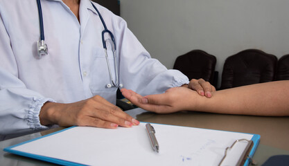 Medicine doctor do physical exam patient's wrist pulse in examination room hospital.