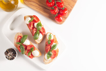 Tomato, basil and cheese fresh made caprese bruschetta. Italian tapas, antipasti with vegetables, herbs and oil on grilled ciabatta and baguette bread. Sandwich.