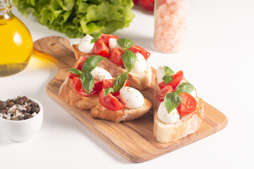 Tomato, basil and cheese fresh made caprese bruschetta. Italian tapas, antipasti with vegetables, herbs and oil on grilled ciabatta and baguette bread. Sandwich.