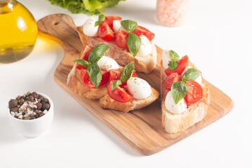 Tomato, basil and cheese fresh made caprese bruschetta. Italian tapas, antipasti with vegetables, herbs and oil on grilled ciabatta and baguette bread. Sandwich.