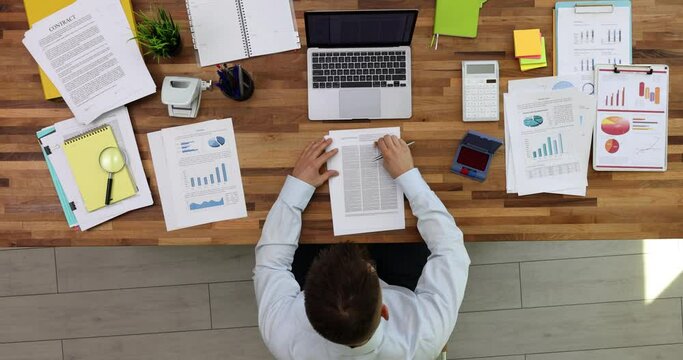 Businessman puts a stamp on documents on the desktop in office top view. Decision was made loan agreement or execution of business transaction was approved