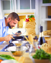 Man following recipe on digital tablet and cooking tasty and healthy food in kitchen at home