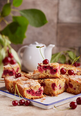 Sponge cake with cherries and almond petals, covered with sugar powder. Delicious homemade sweet pie bars with seasonal berries. 