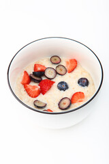 Oatmeal porridge with strawberries and blueberries. Healthy breakfast. Vertical photo .Copy space. Isolated object.