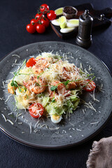 Caesar salad with shrimp.On a dark background. Without people. Vertical photo.