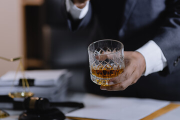 Law holding a glass of whiskey at desk, justice and law, attorney, court judge, concept.