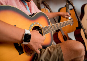 Young musician tuning a classical guitar in a guitar shop