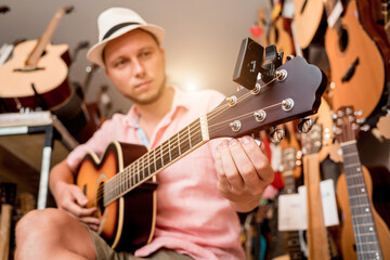 Obraz premium Young musician tuning a classical guitar in a guitar shop