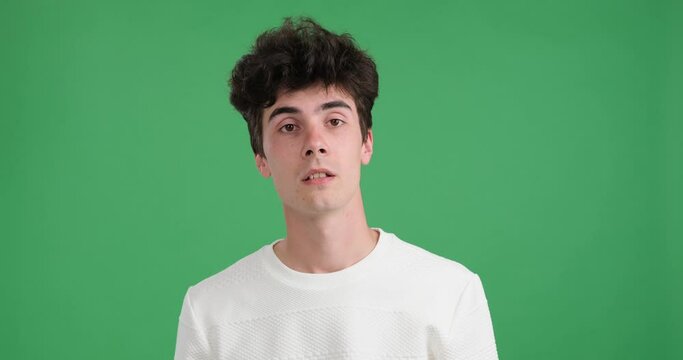 Caucasian man on vibrant green backdrop. With widened eyes and a startled expression, he reacts to something falling from above, capturing the essence of surprise and alarm.