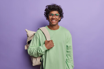 Photo of cheerful Hindu male backpacker or tourist smiles pleasantly leads active lifestyle and...