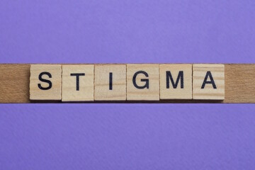 word stigma made from wooden gray letters lies on a lilac background
