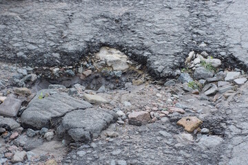 one big pothole on the gray asphalt and in the ground on the road on the street