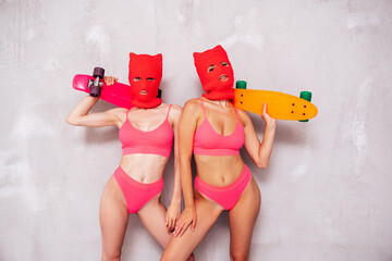 Two beautiful sexy women in red underwear. Models wearing bandit balaclava mask. Hot seductive...