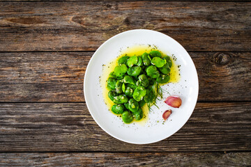 Broad beans with garlic and dill on wooden table
