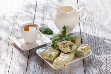 nougat with nuts on a white dish on a wooden table in the sun