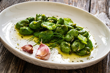 Broad beans with garlic and dill on wooden table
