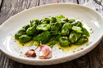 Broad beans with garlic and dill on wooden table
