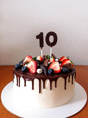 Delicious beautiful birthday cake with the number 10. Pastries with berries and chocolate