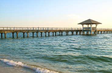 Long wooden pier on the blue tropical windy sea