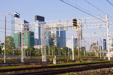 Fototapeta premium Railway traction in the metropolis, electric traction poles, skyscrapers in the background, development of infrastructure and train transportation.