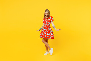 Full body side profile view young cheerful smiling satisfied fun caucasian woman she wear casual clothes spinning in red dress isolated on plain yellow background studio portrait. Lifestyle concept