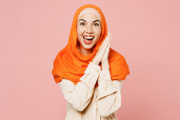 Young arabian asian muslim woman wear orange abaya hijab lok camera hold arms together clap...