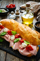 Big sandwich with mortadella with pistachios and mozzarella cheese on wooden table
