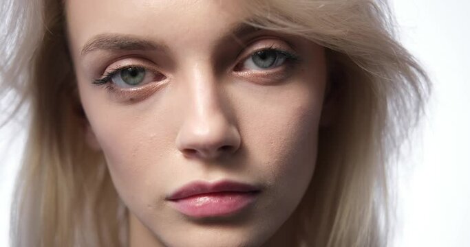 Close-up portrait of a sorrowful Caucasian woman standing against a pristine white background. Her face in exquisite detail, emphasizing the profound sadness etched on her features.