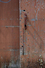 A rusty steel handle on a wooden panel